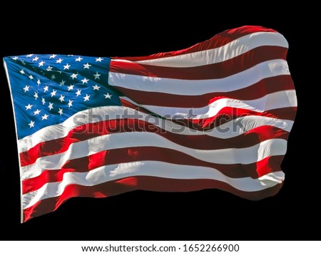 American flag blowing in the wind isolated against a black background.