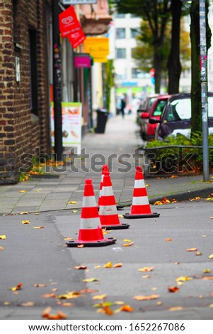 A vertical shot of three traffic cones next to each other on the street