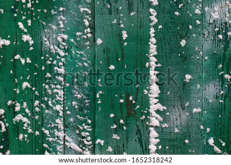 Snow covered green wooden fence texture, shot closeup