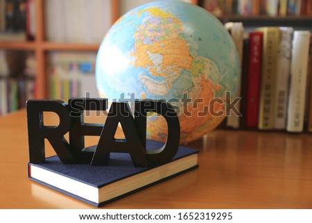 Picture of the English alphabet on the table in the library Bookshelf and globe in the background selective focus and shallow depth of field