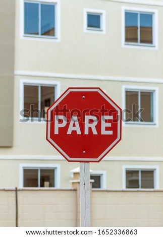 A stop sign in Brazil (Portuguese). Stop sign with buildings background.