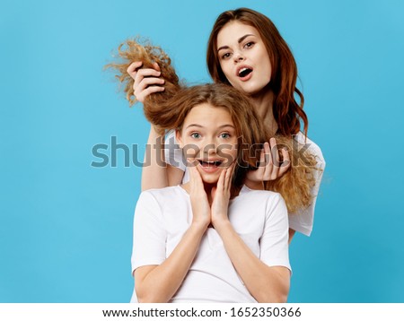 A woman examines the hair on her head to a girl on a blue background