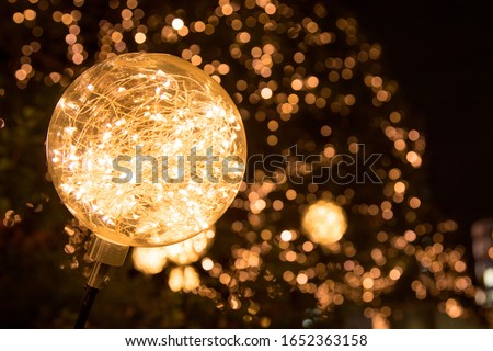 Up close photo of LED string lights inside clear ball with others creating a bokeh background