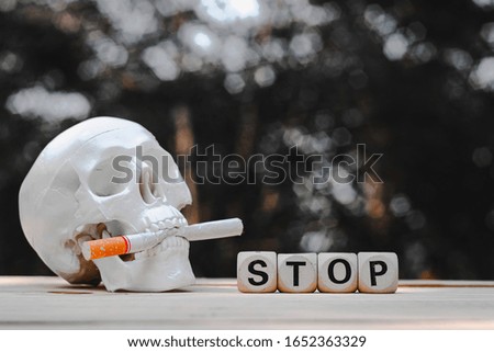 Close up wooden stop text block, skull and cigarette on wood table, 31 may, world no tobacco day concept, vintage tone