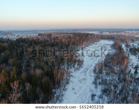 Aerial view winter forest in the rays of the rising sun. Golden winter Dawn. The picture from the drone