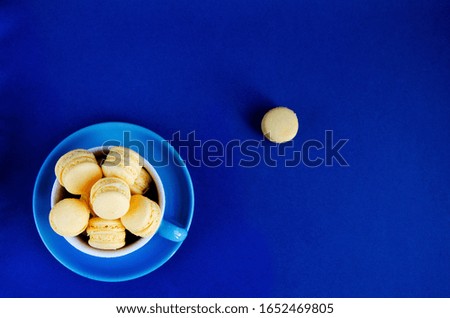 Macaroons in a blue cup on a blue background, the color trend is 2020, the trend of the cup is on top, soft focus, flat lay, horizontal image
