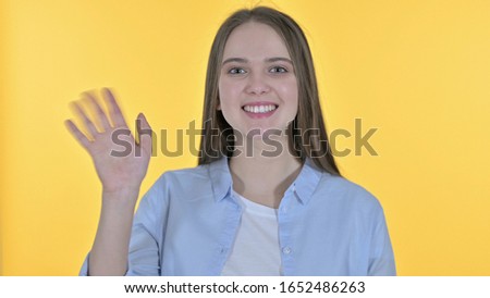Portrait of Cheerful Casual Young Woman Waving at the Camera