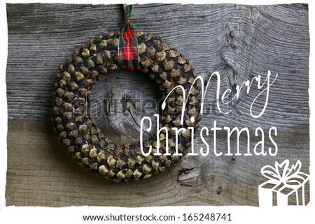 Merry Christmas message, handmade pinecone wreath decoration over rustic Elm wood background - retro style design
