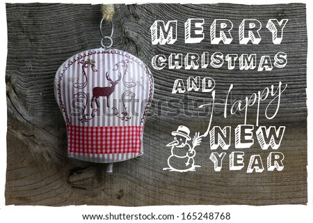 Merry Christmas message, handmade decoration deer on tin bell over rustic Elm wood background - retro style design