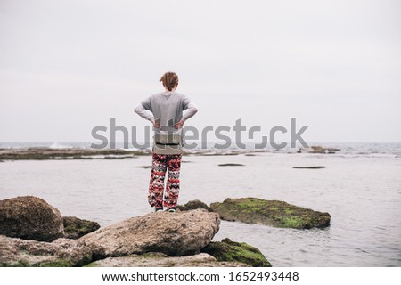 A person standing on the mossy rocks on the body of the water