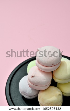 Vibrant marshmallow on black plate on colorful background. Confectionery wallpaper With green yellow pink and purple sweets, candy shop, place for text
