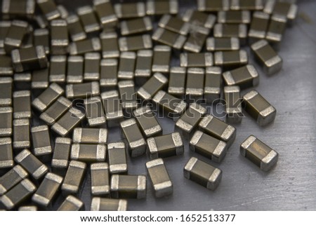 Abstract close-up of 0603 SMT surface mount MLCC capacitors electronics components random scatter in storage container Royalty-Free Stock Photo #1652513377