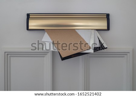 Letters, flyers  and utility demands, posted through a domestic letterbox. Paper waste reduction concept. Royalty-Free Stock Photo #1652521402