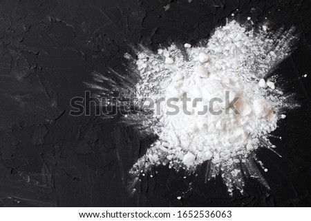 Corn starch on a black background, top view, copy space. Corn white starch on a black table. Potato starch on a black background. Top view, copy space. Royalty-Free Stock Photo #1652536063