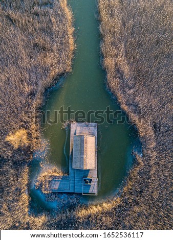 A small hut in a reed field in the middle of the Schilfgürtel of Neusiedler See near Breitenbrunn in Burgenland Austria on a cold winter morning with frozen water