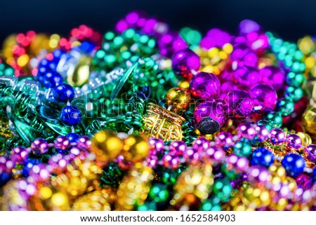 A colorful group of plastic festival beads with a dark bluish background.  Selective focus.  Blurred foreground.  Blurred background.  
