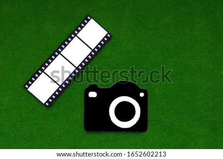 Camera, a photographic film on a green background. Photography, reativity.
