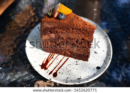 Chocolate cake with strawberry and blueberry in white dish on the table in restaurant and sunlight. Selective focus
