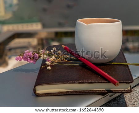 Workplace area with laptop, fruit juice mug flower and notebook with pencil Comfortable office work table and blurry city view. Selective focus.