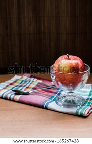 Still life with three red apple in glass of ice cream and spoon on table