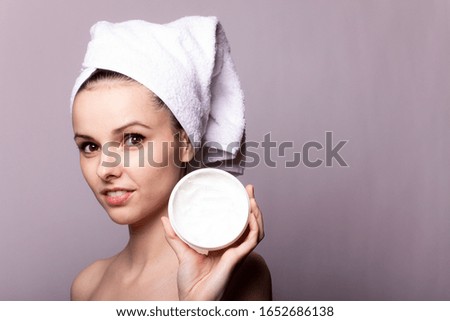 girl with a white towel on her head and a can of cream in her hands, gray background