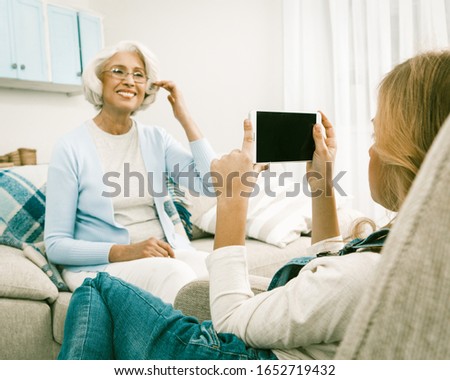 Granddaughter Making Photos Or Video Of Her White Haired Italian Granny On Smart Or Mobile Phone While Staying At Home For Seasonal Holidays, Fashion Concept