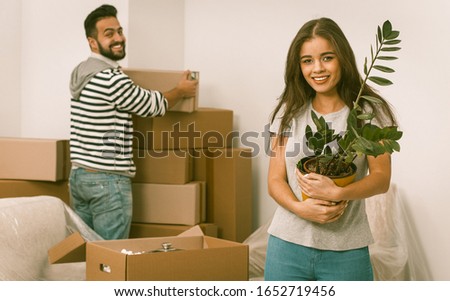 Smiling young adults moving in new home man and woman unpacking boxes standing in new apartment unpacking boxes.