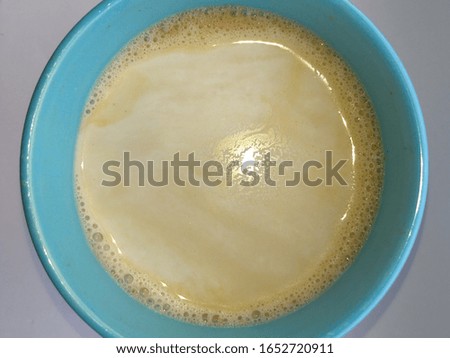 a cup of coffee with cream golden highlight appetizing drink in a mug of aquamarine color