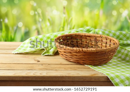 Empty basket with tablecloth on wooden table over green bokeh background. Spring and easter mock up for design. Royalty-Free Stock Photo #1652729191