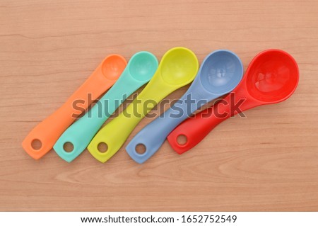 Close up of five measuring spoons on wood grain table