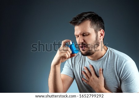 Portrait of a man with an asthma inhaler in his hands, an asthmatic attack. The concept of treatment of bronchial asthma, cough, allergies, dyspnea Royalty-Free Stock Photo #1652799292