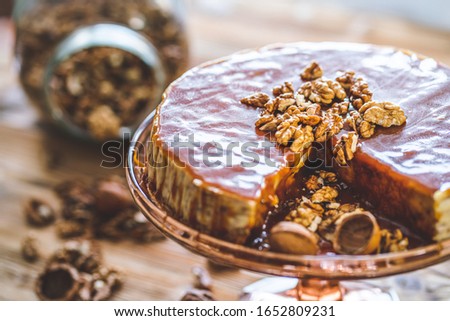 Sweet homemade chessecake with caramel topping and walnut nuts on wooden table. Tasty brown cake dessert.