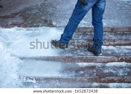 a man walks up stairs with ice steps, poor work of public utilities Royalty-Free Stock Photo #1652872438