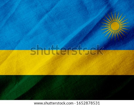 Flag of Rwanda on creased fabric background.