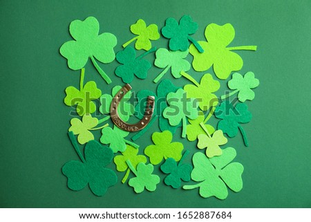 Flat lay composition with clover leaves and horseshoe on green background. St. Patrick's day