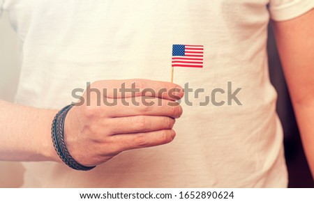 American Citizen, Man holding small paper USA Flag, concept toned picture 