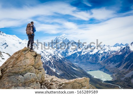 hiker at the top of a rock with backpack enjoy sunny day  Royalty-Free Stock Photo #165289589