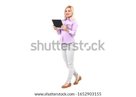 Portrait of a charming young woman working on tablet pc and standing over white background