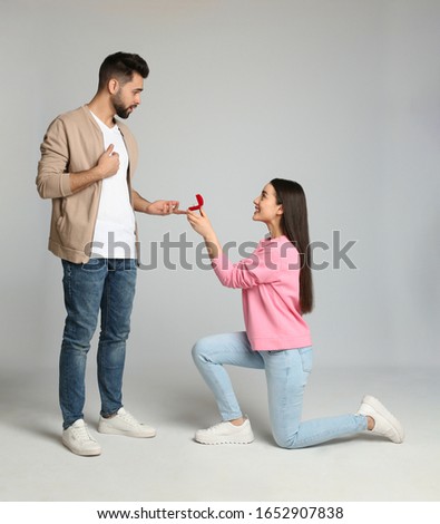 Young woman with engagement ring making marriage proposal to her boyfriend on light grey background Royalty-Free Stock Photo #1652907838