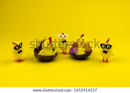 hatching chickens on a yellow background, with glasses in a nest, on a yellow background d