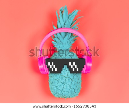 Pineapple in pink headphones and pixel glasses on a coral background