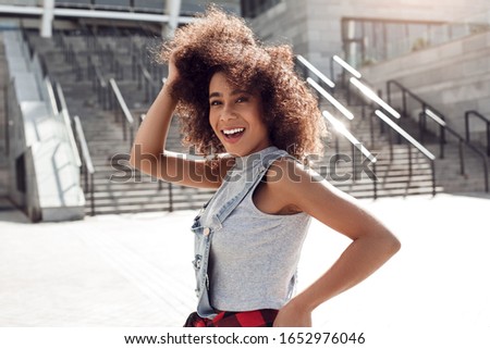 Young stylish woman in the city street standing on concrete stairs smiling toothy cheerful