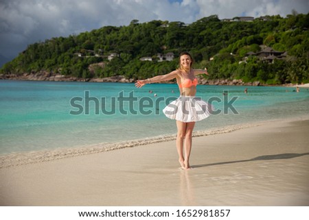 Woman is enjoying a beach vacation, having fun on the white sand beach. Happy woman. Mahe, Seychelles