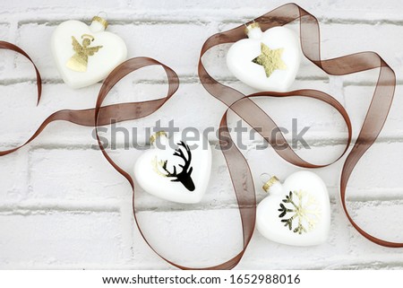 White Christmas ornaments to hang on Christmas tree, decorated with golden silhouettes of angel, star, reindeer and snowflake. Heart-shaped spheres. Christmas concept.