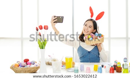 Beautiful Asian women bunny girl, Taking a selfie picture of colorful Easter eggs with a mobile smartphone, Happy lady preparing for Easter , She painting Easter eggs at home, banner for website