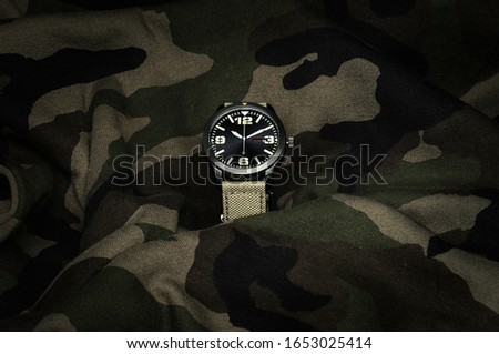 Military watch on camouflage background