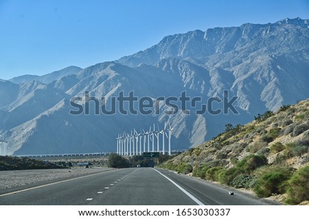 Road Leading to Line of Windmills with Mountain Background and Hill of Desert Plants