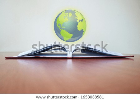 The globe floats on the book, a book is placed on the brown table in the university library.