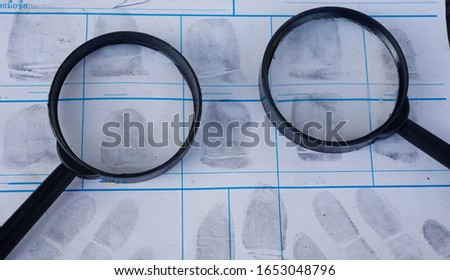 Magnifying glass on fingerprint crime page file.Concept of finding evidence in criminal. Royalty-Free Stock Photo #1653048796
