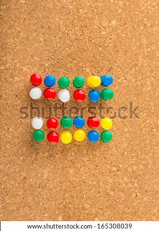 Equal sign made of push pins on cork background